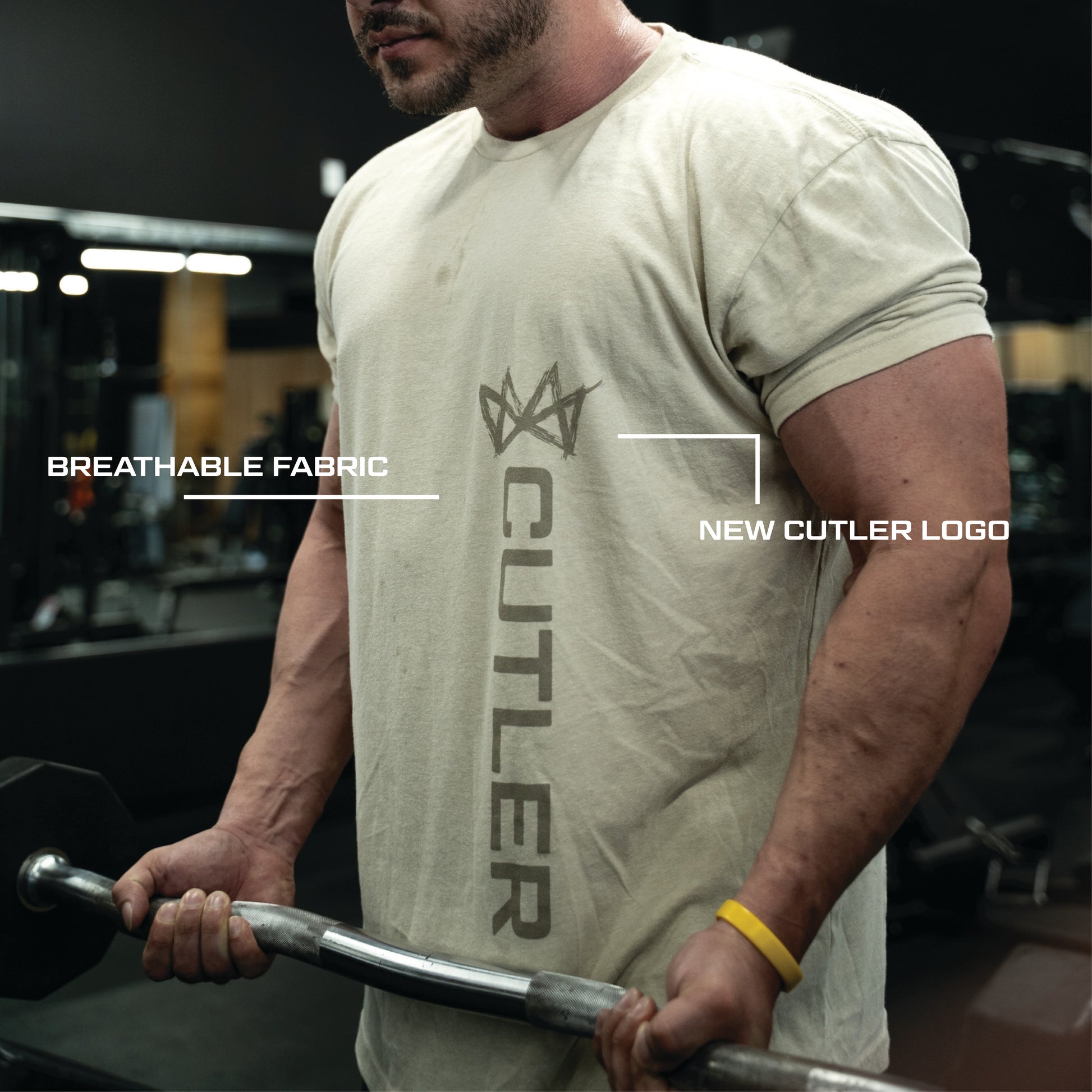 Person wearing a light beige  t-shirt with new 'Cutler' branding, holding a barbell in a gym setting.