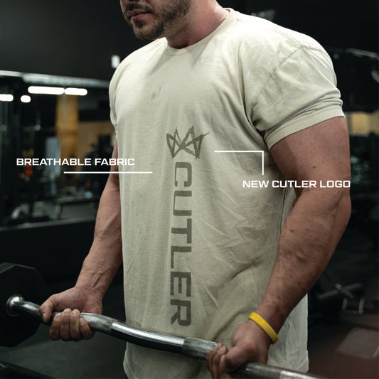 Person wearing a light beige  t-shirt with new 'Cutler' branding, holding a barbell in a gym setting.